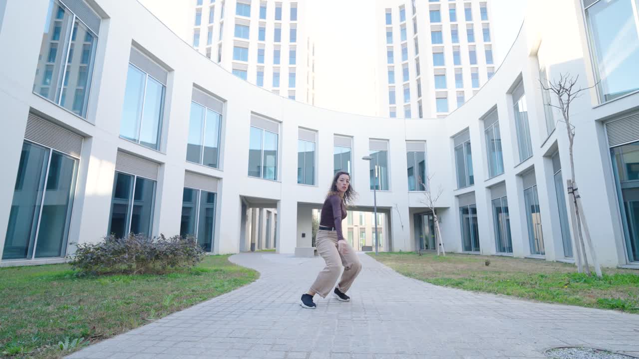 Young energetic female dancer performing modern dance moves outdoors