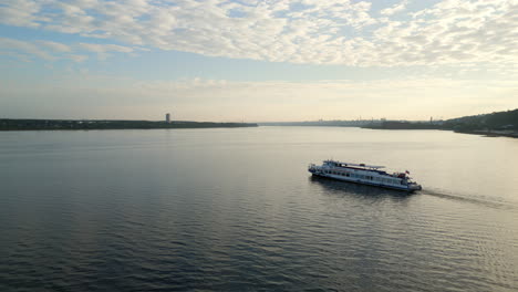 passenger boat cruising on a wide river under a cloudy sky