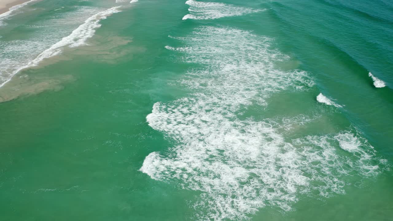 disparo volador de un dron sobre las olas que se estrellan en la playa