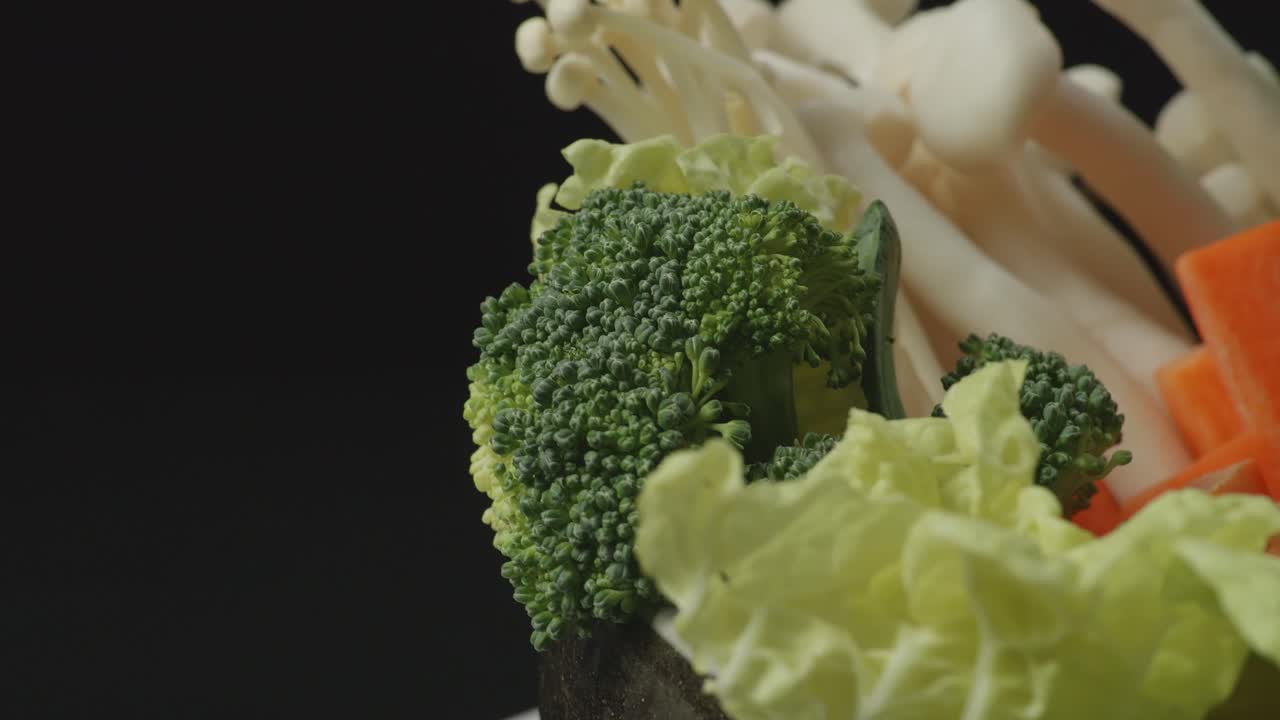 Close Up Of A Pot Of Shabu Ingredients Spinning Around On The Black Background
