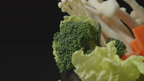 cerca de una olla de ingredientes de shabu girando en el fondo negro