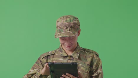 close up of asian man soldier using a tablet while standing in the green screen background studio