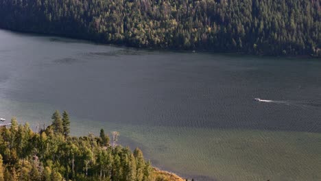 boat driving on paul lake by kamloops on a sunny day in fall