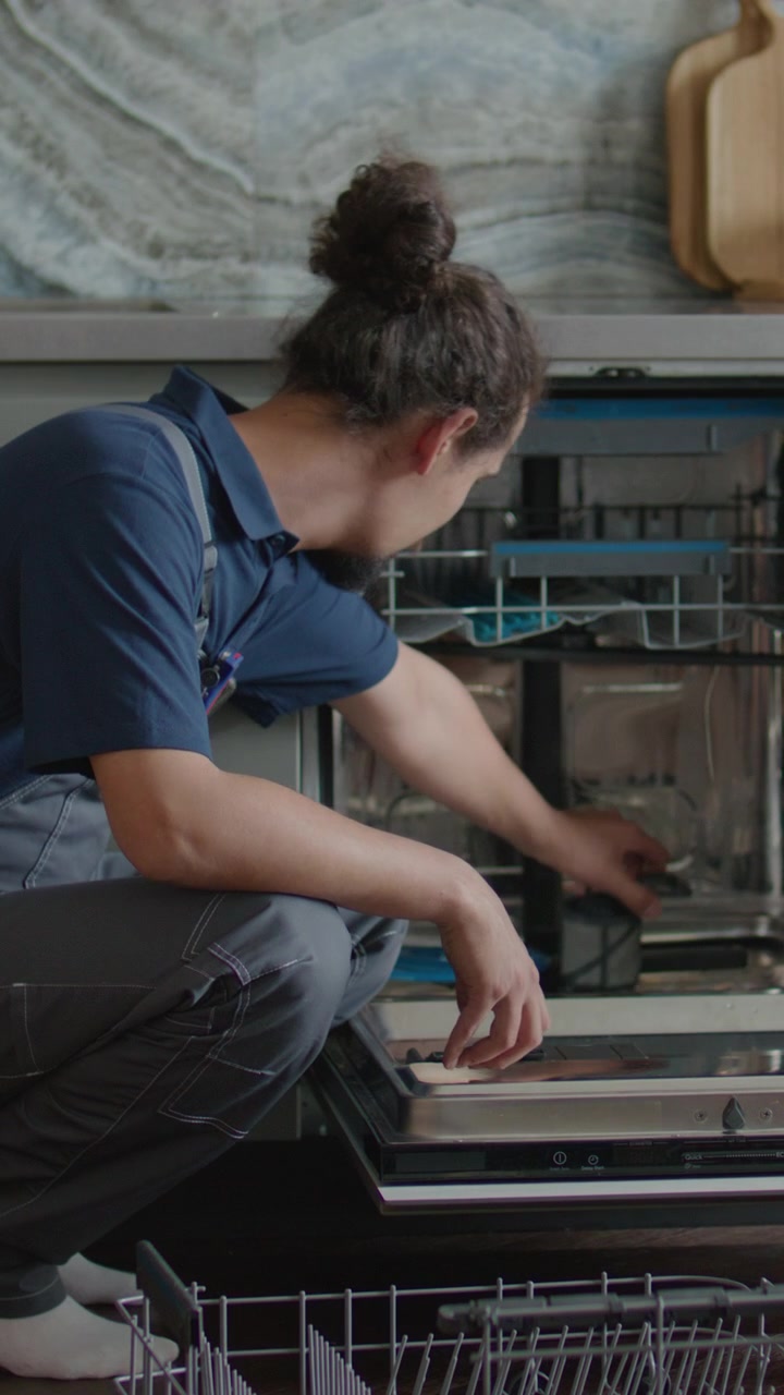 Repairman Inspecting Filter inside Broken Dishwasher in Home Kitchen