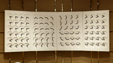Multiple simple clockwork artwork creating patterns hanging framed in luxury watch store, static shot