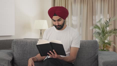 happy sikh indian man reading book and drinking tea