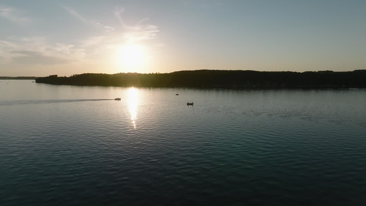 toma de drones en órbita de las siluetas de barcos de pesca y pontones en un lago al atardecer