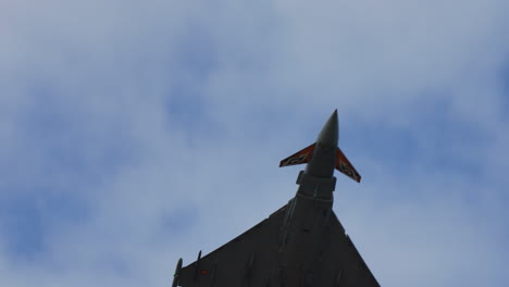 military fighter jet seen from below during aerial stunt with decorated tail wings and visible details