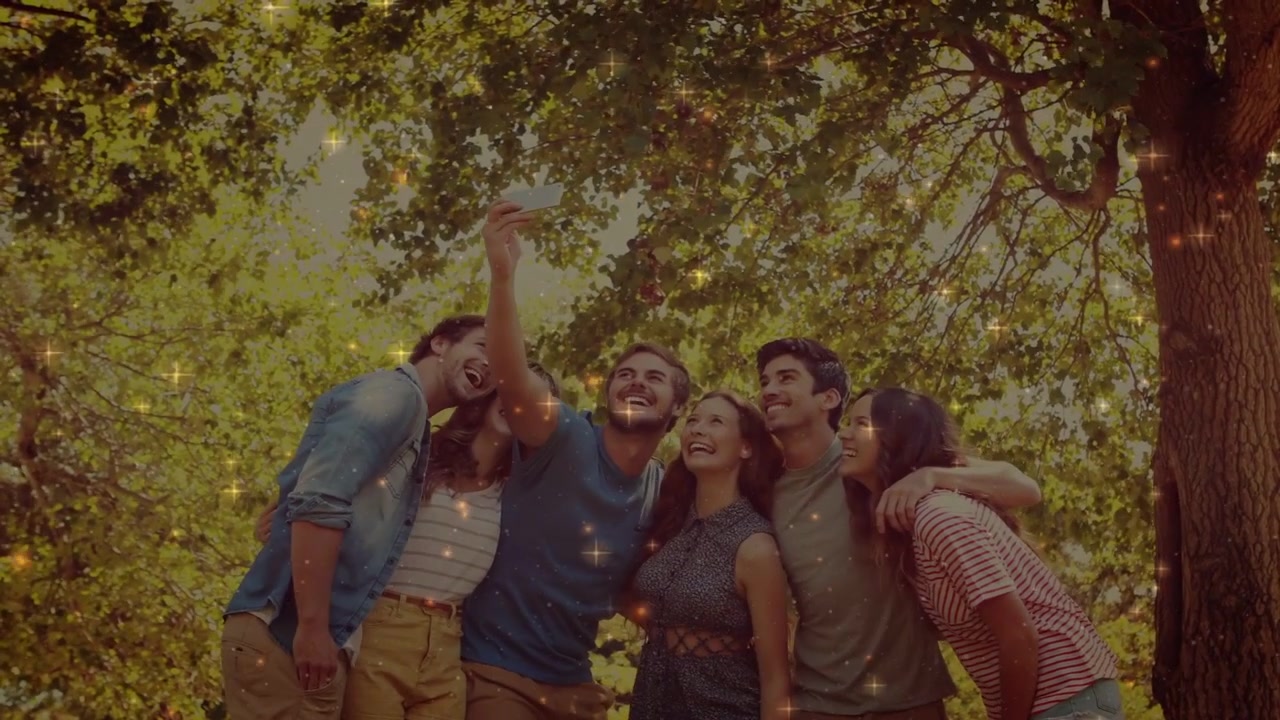 Hombre levantando el teléfono para tomar una selfie bajo un árbol, un grupo reaccionando con destellos para redes sociales.
