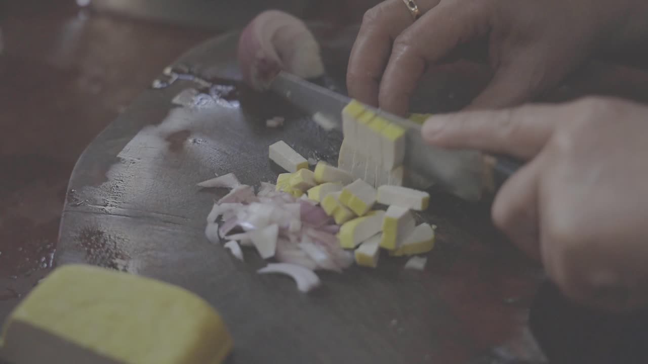 Cooking Pad Thai Series: SLO MO chef's hand cutting tofu into dices on chopping board at Thai street food shop