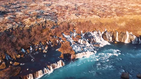 drone with cinematic movements shows beautiful icelandic waterfall, hraunfossar, in sunset light from multiple angles