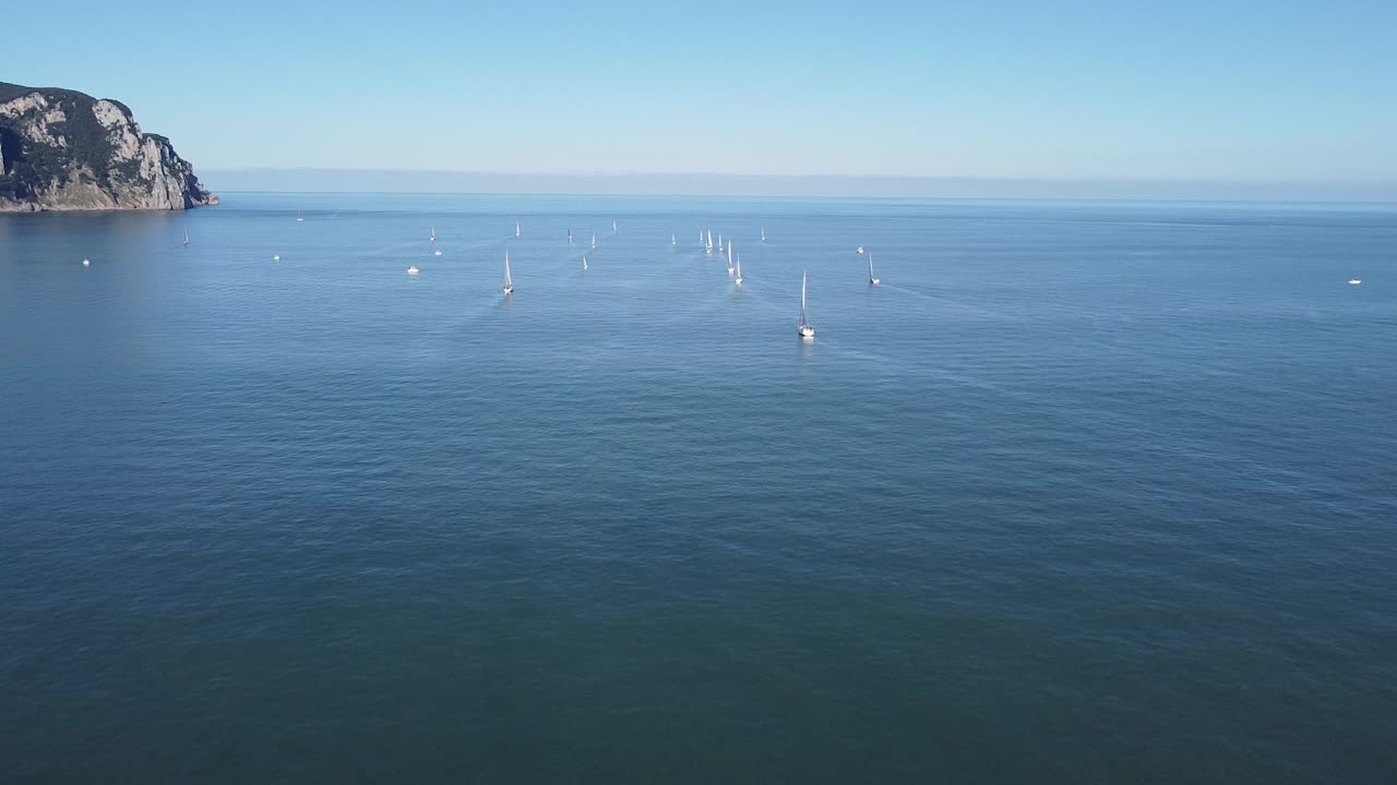 Sailboats floating in rippling endless blue sea under cloudless sky. Aerial view