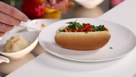 preparando un perrito caliente con salsa