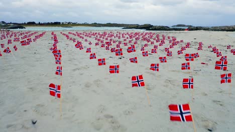 muchas banderas noruegas en filas en la playa de arena, ángulo bajo, vista aérea sobrevolando