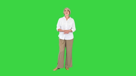 cheerful senior woman talking to camera on a green screen, chroma key