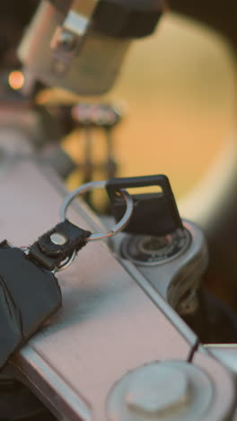 un primer plano de la mano de una persona quitando delicadamente una llave de la ignición de una motocicleta