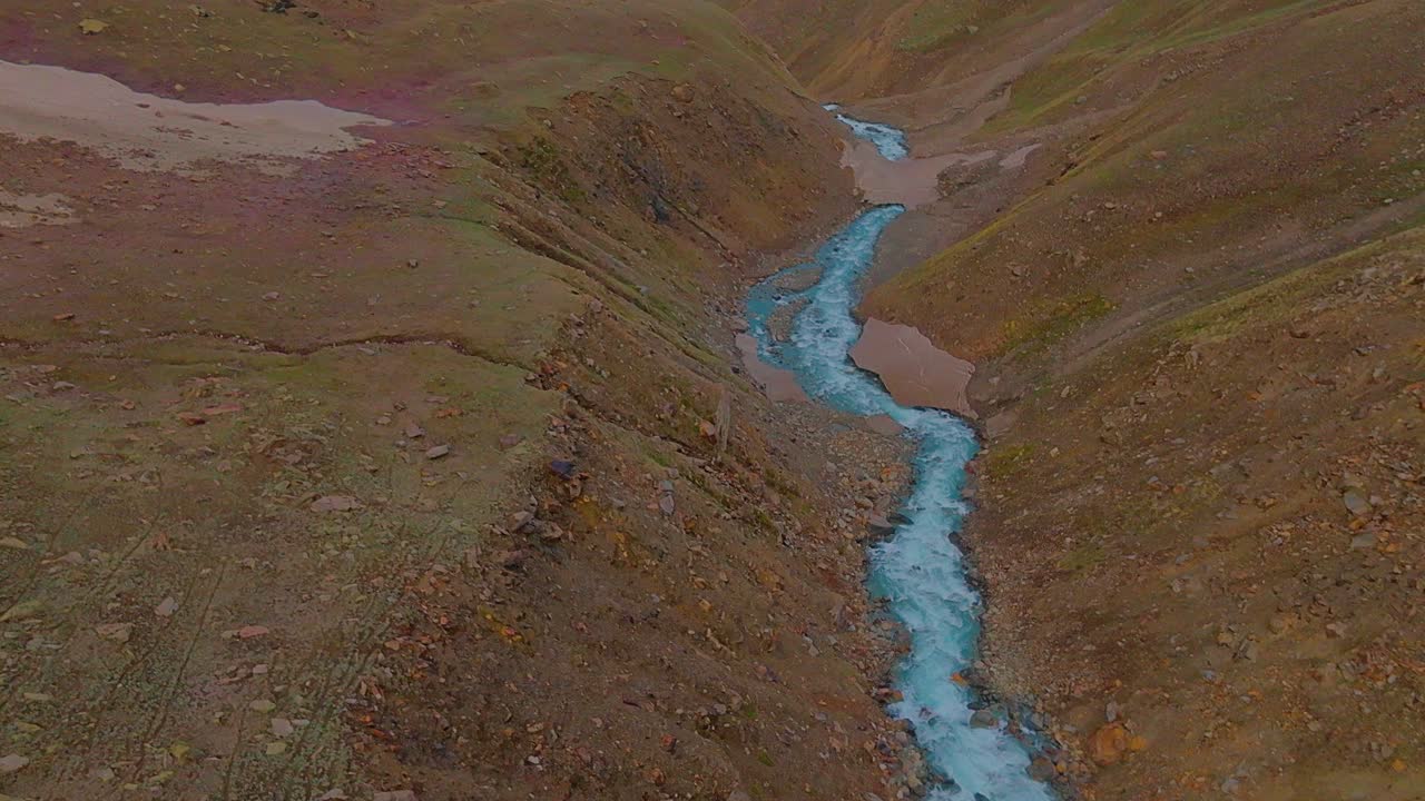4k fly forward drone shot volando a lo largo de un río glacial revelando una cordillera del himalaya cubierta de nieve con un cielo de amanecer dorado