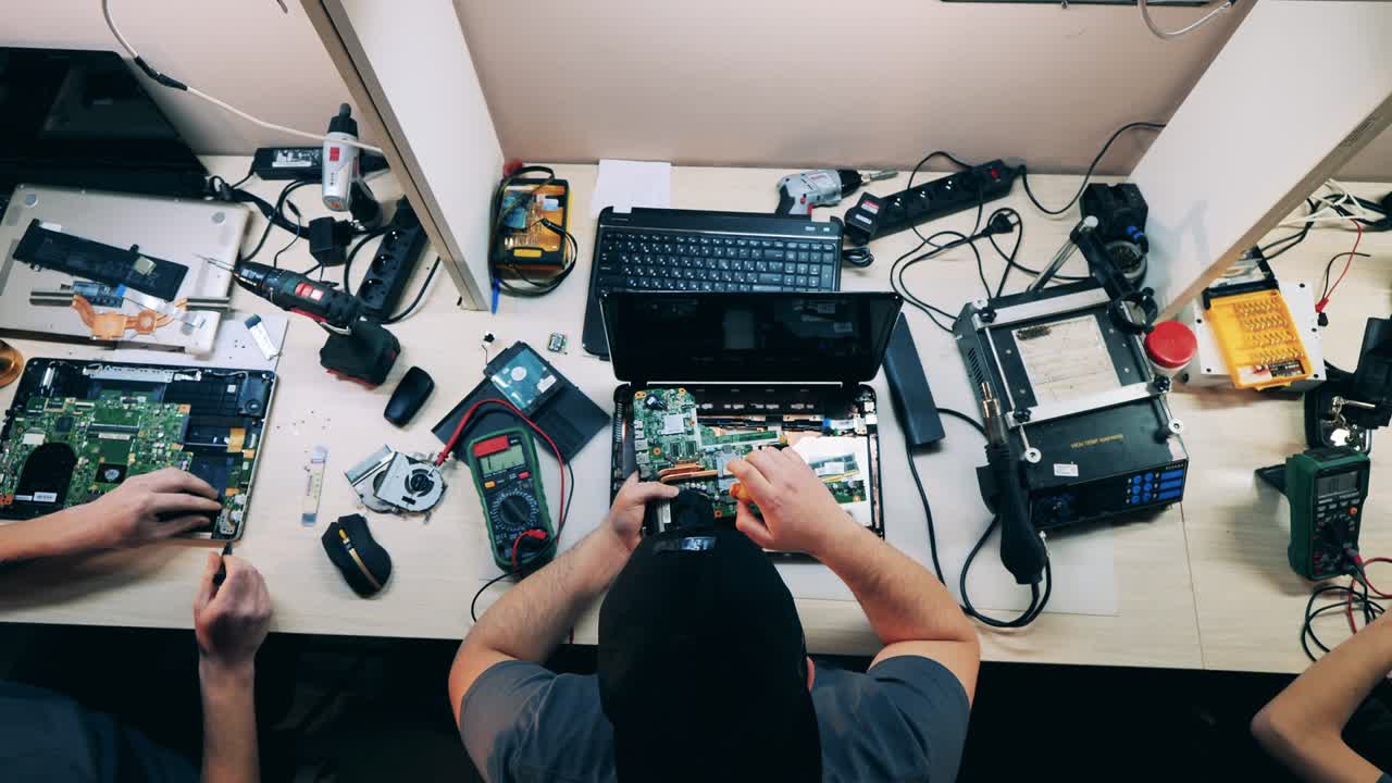 vista de arriba de un reparador desmontando una computadora portátil