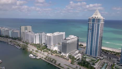 Epische-Gerade-Drohnenaufnahme-Der-Collins-Avenue-Mit-Den-Modernen-Eigentumswohnungsgebäuden-Am-Meer-Und-Wunderschönem-Blick-Auf-Das-Wasser