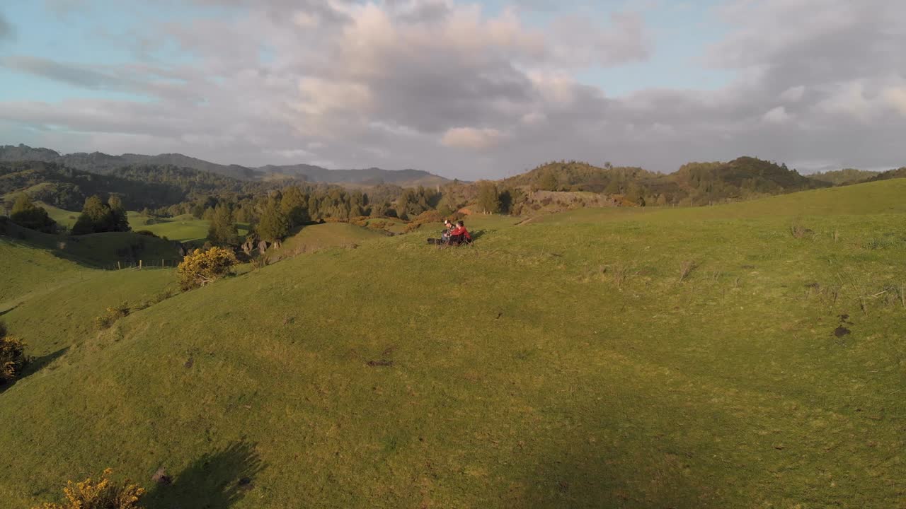 시골 풍경의 언덕에 앉아있는 커플의 원형 공중 풍경