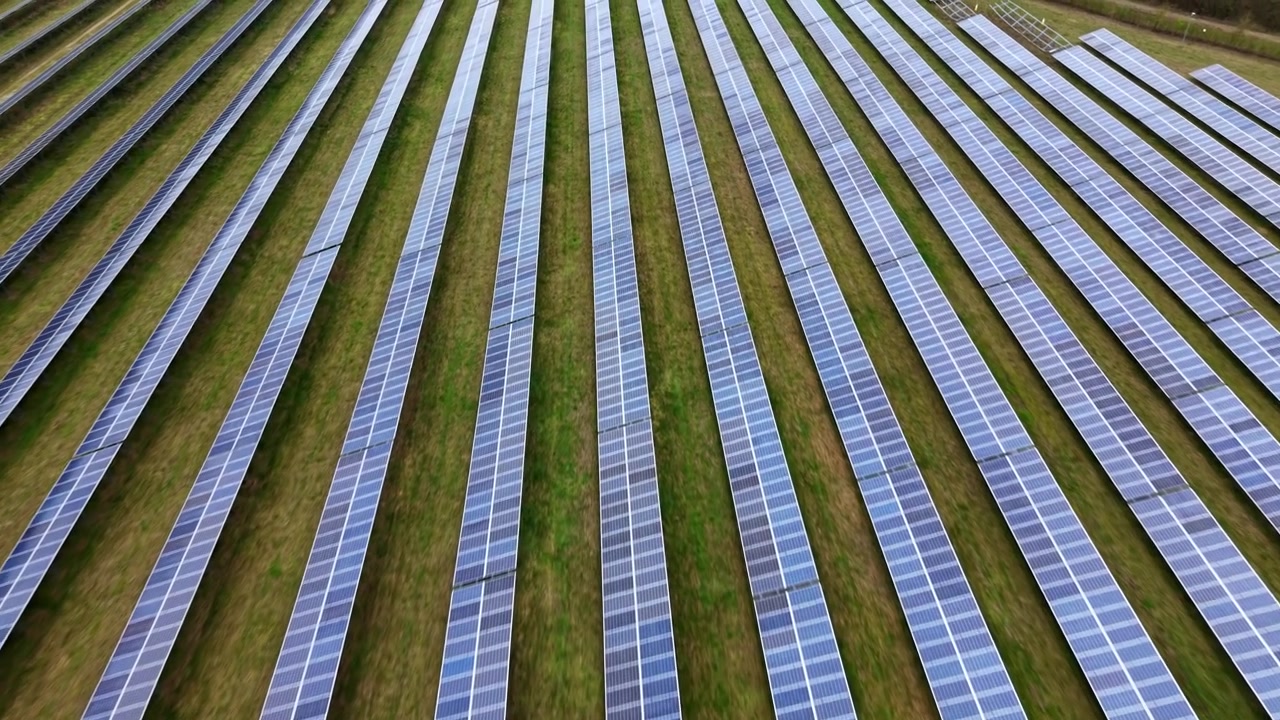 Forhøjet luftfoto fra høj vinkel, der viser en omfattende solcellepark for vedvarende energi bygget på åbne landbrugsarealer i Storbritannien