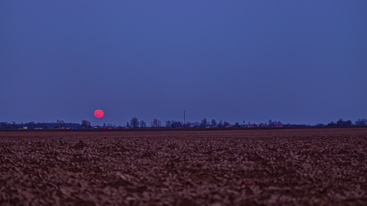 el lapso de tiempo de la luna es de un color carmesí brillante a medida que asciende hacia el cielo