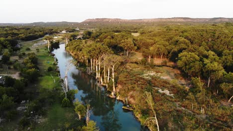 Rising-high-above-section-of-cypress-trees-along-the-river-at-sunset