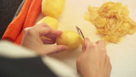 Manos-Femeninas-Pelando-Patatas-En-La-Cocina-A-Cámara-Lenta