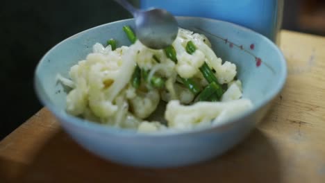 coliflor recién hervido y frito y frijoles verdes siendo agitados en un cuenco, filmado como un disparo en cámara lenta de cerca con movimiento de estilo deslizante