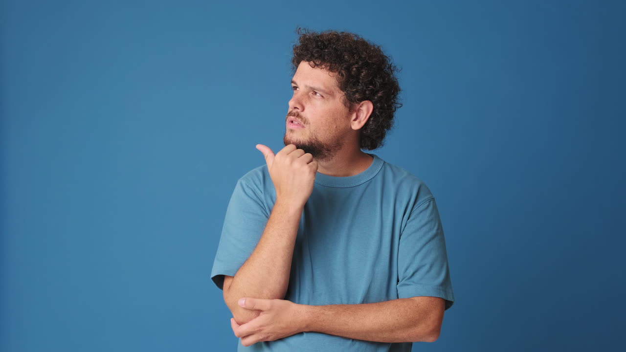 Man Pondering, Then Smiling and Pointing at Camera