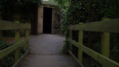 walking over small wooden bridge leading to a doorway medium shot