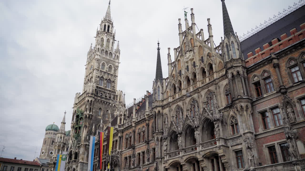 A closer look at the intricate Neo-Gothic facade of the New Town Hall (Neues Rathaus) at Marienplatz, Munich, with the Frauenkirche’s iconic domes in the background.