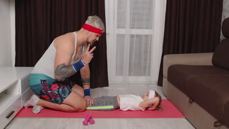 Hombre-Entrenador-Deportista-Trabajando-Con-Una-Niña,-Ejercicios-Abdominales-Con-Su-Hija-En-Casa-En-La-Alfombra