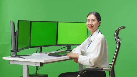 woman at computer with green screen monitors