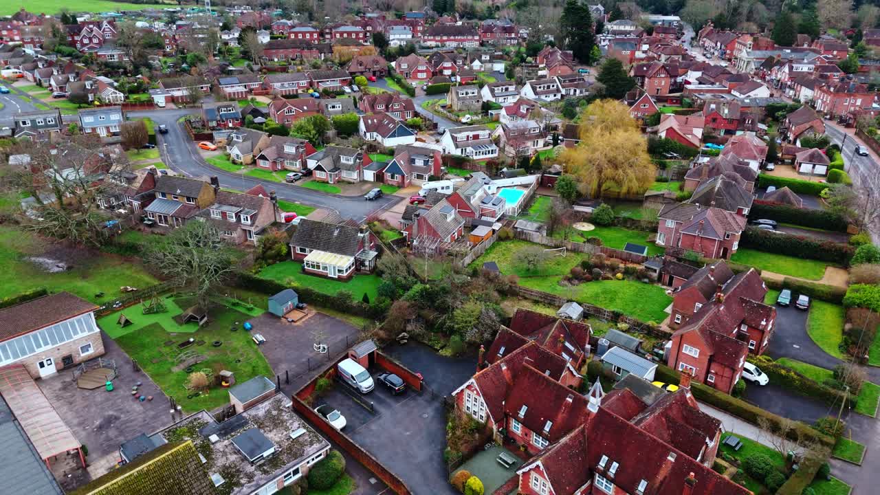 Svepande drönarbild från luften över förorts-Southampton med bostäder i Botley by vid solnedgången en mulen, molnig vinterdag, med bilar som passerar på vägarna nedanför förbi småhusen i staden.
