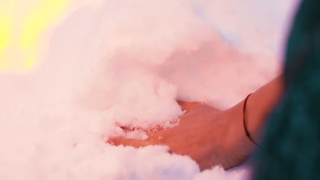 middle-aged-lady-hand-touches-snow-near-burning-fire-closeup