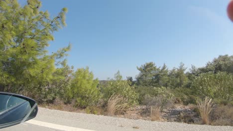 Watching-out-of-the-side-window-of-a-car,-while-driving-down-some-beautiful-roads-at-Rhodes-island-Greece