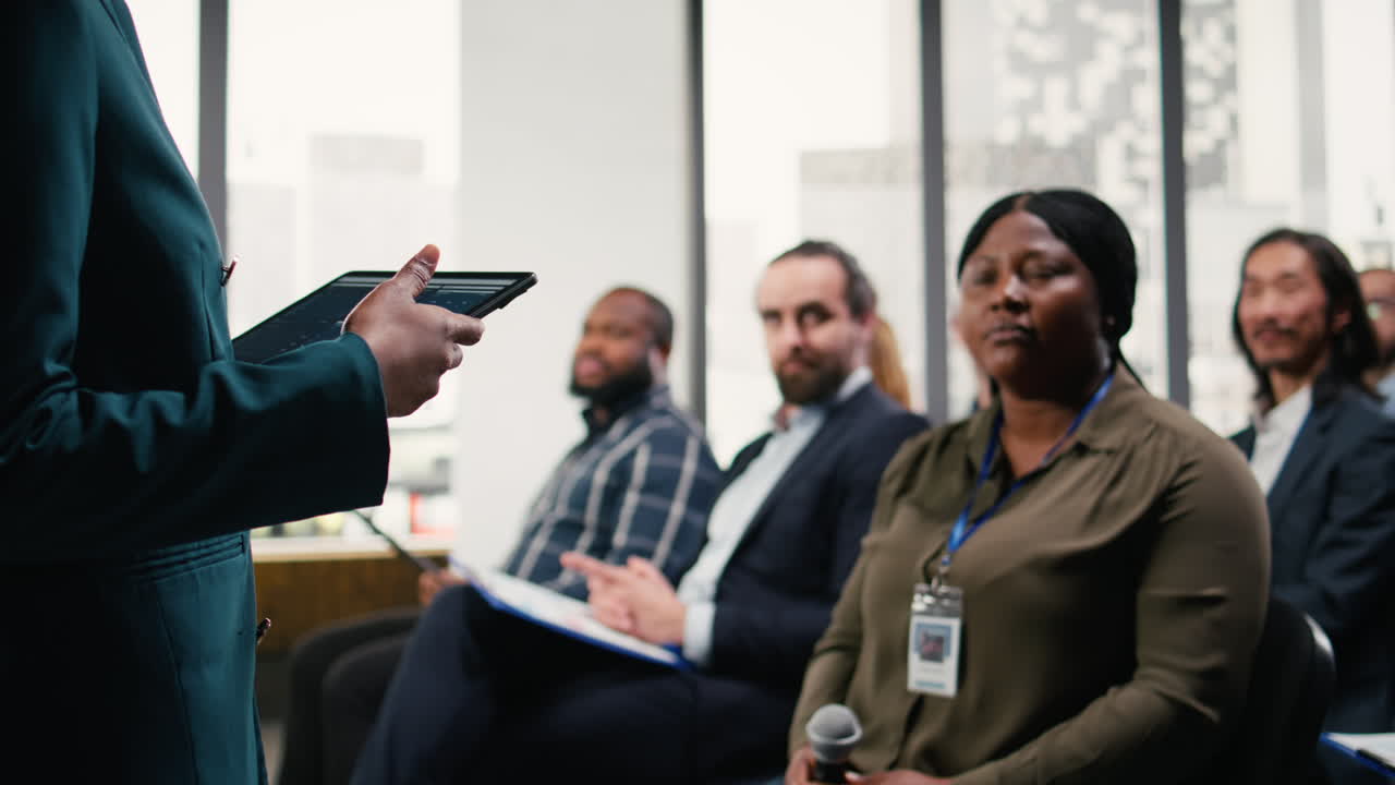 Black guest speaker hosting corporate business forum with panel discussion