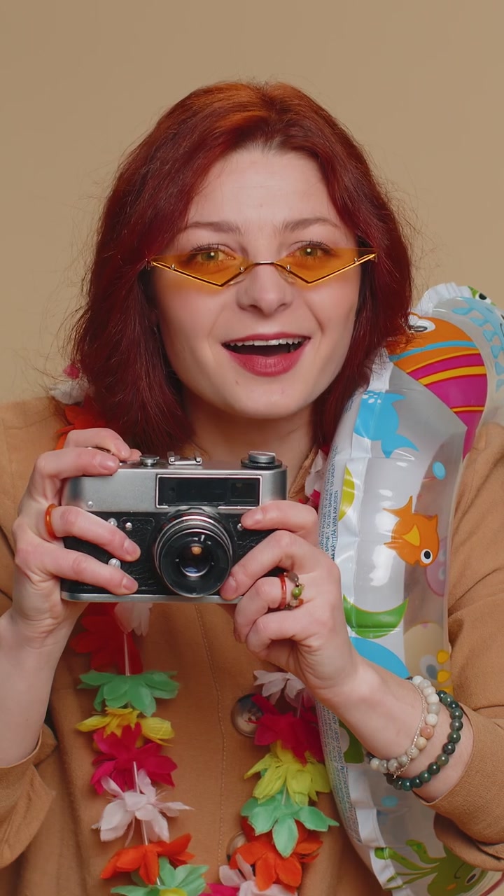 Fortunata giovane fotografa turistica che scatta foto con una telecamera retro e sorride in vacanza