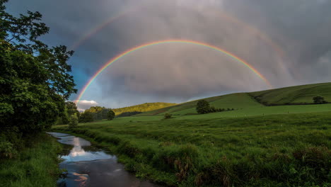 colorful double rainbow over a green valley