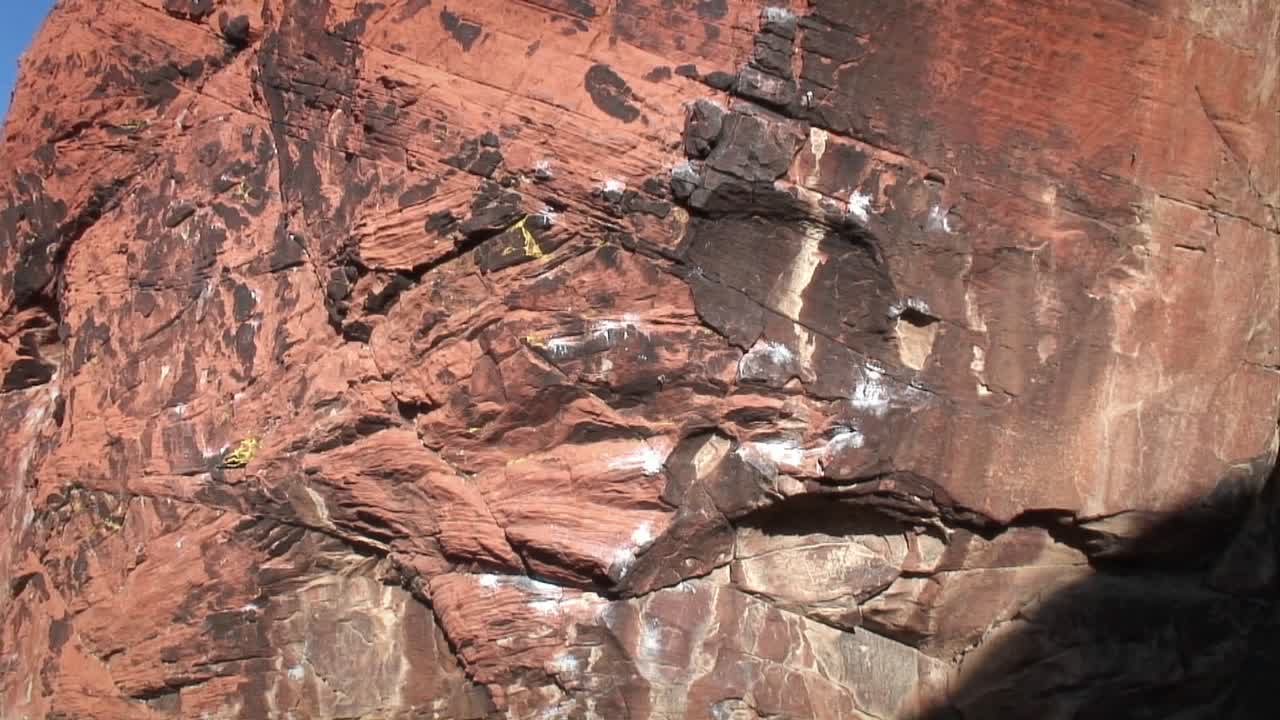 un escalador asciende por una pared rocosa