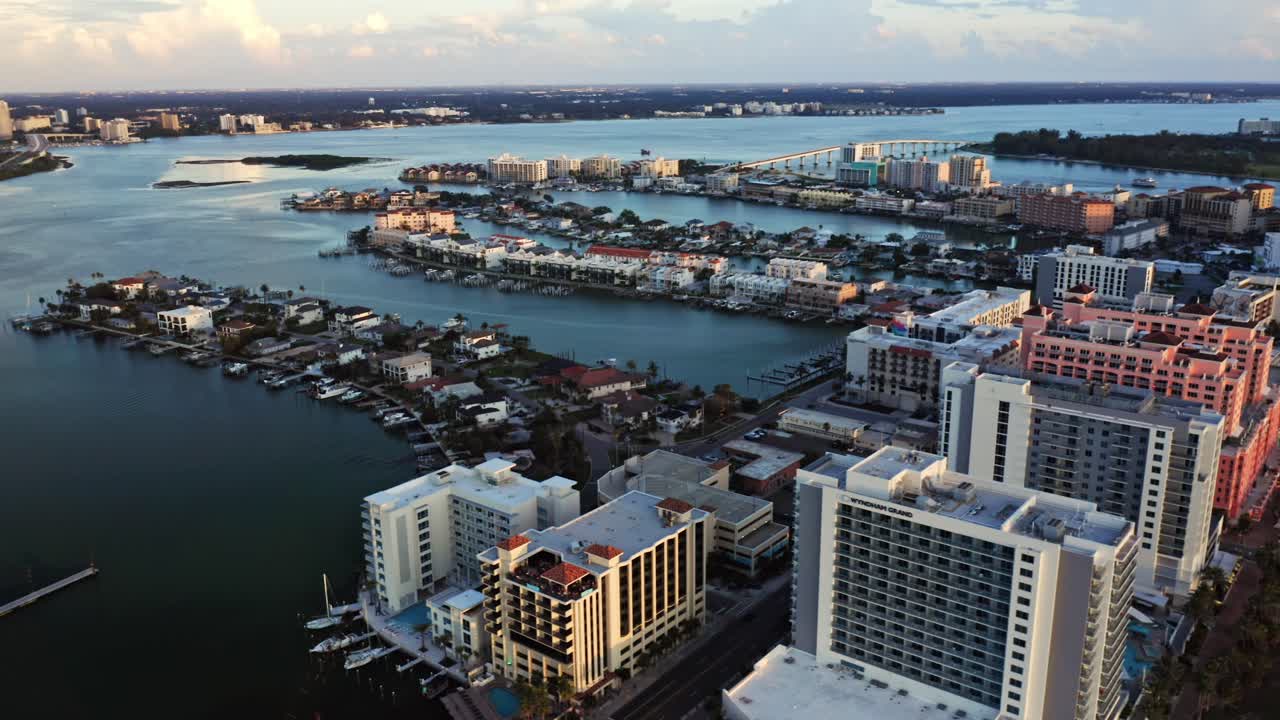 High-rise beachfront hotels rise beside a wide sandy shoreline while nearby waterways and residential islands create a scenic blend of urban and coastal landscapes
