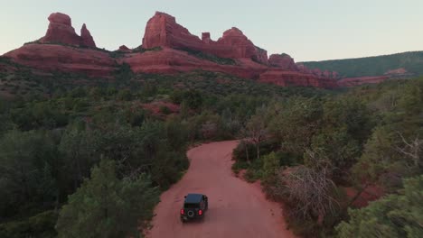 off-road compact suv driving on dirt road to the sandstone formations in sedona, arizona