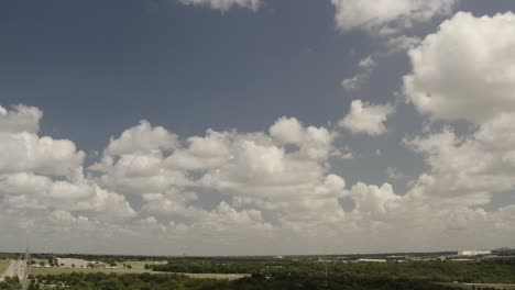 un pequeño avión vuela en los cielos azules y las nubes blancas hinchadas sobre las carreteras rodeadas de árboles verdes