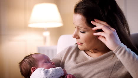 anxious new mother suffering with post natal depression holding sleeping baby girl in nursery at home