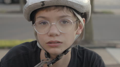 Un-Niño-Lindo-Con-Casco-De-Bicicleta-Y-Anteojos-Gira-Y-Mira-A-La-Cámara