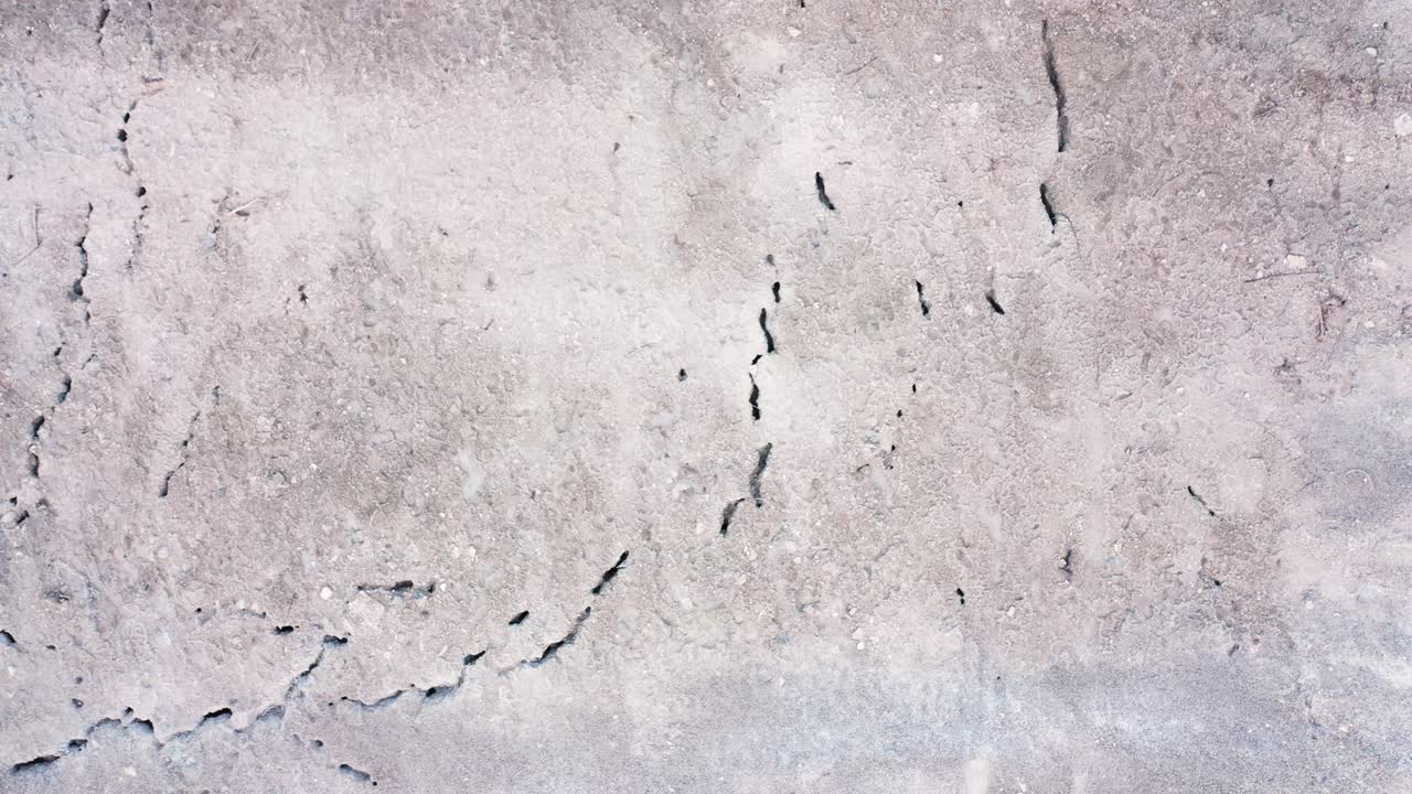 High aerial top down shot over desert landscape showing texture and cracks in the earth