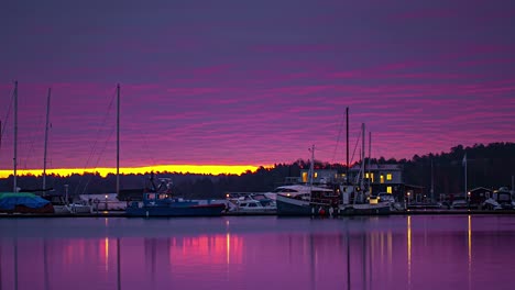 stunning and colorful sunrise at a shoreline dock with the sky reflecting off the water - time lapse