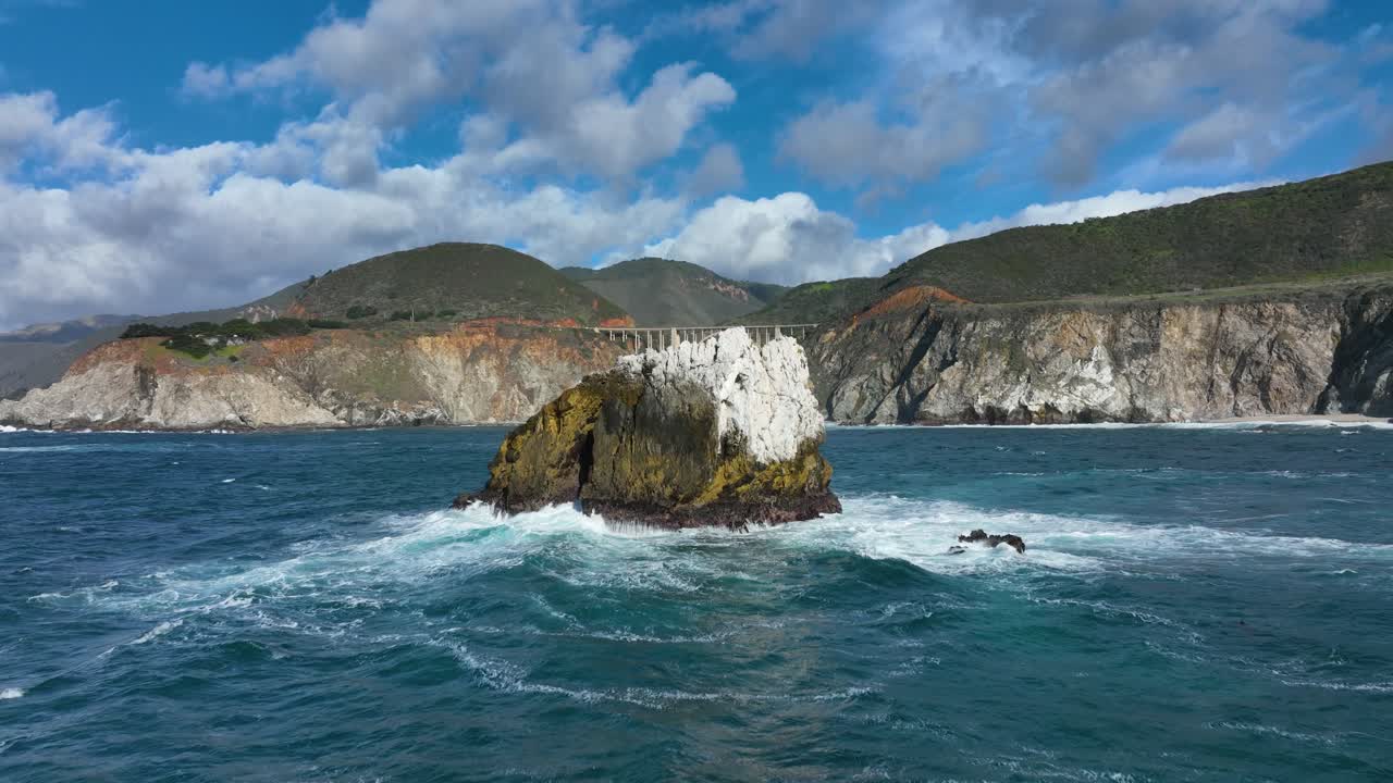 toma aérea que revela el puente bixby mientras las olas rompen contra las rocas en la costa del pacífico, big sur highway 1