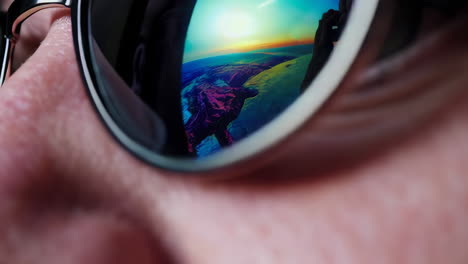 close-up reflection in sunglasses of landscape and person with camera